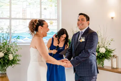 Ellie officiating an intimate Gold Coast wedding ceremony, smiling as the couple hold hands