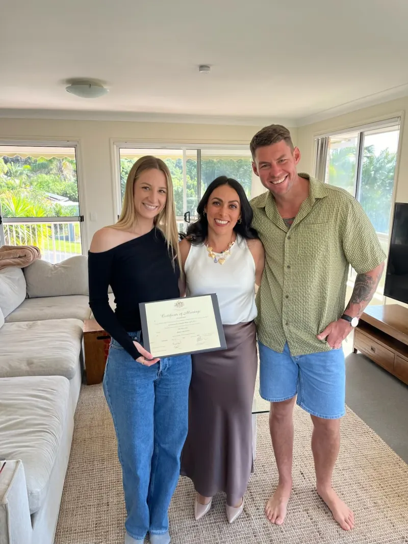 Ellie with a couple holding their marriage certificate at a home elopement on the Gold Coast
